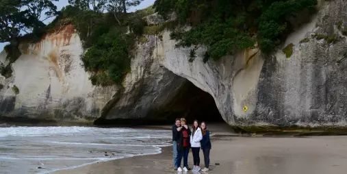 Visitors standing on the beach near the Cathedral Cove cave entrance