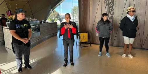 A group of people gathered inside a modern South Auckland café at the start of the Auckland Urban Māori Experience cultural tour, with Māori design elements in the background.