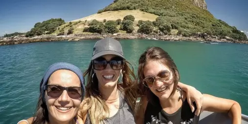 Group of friends taking a selfie with Mount Maunganui in the background on a cruise