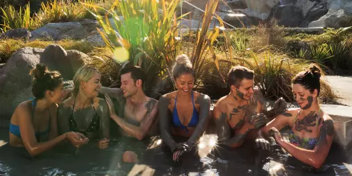Group of friends applying geothermal mud while soaking at Hell’s Gate Rotorua.