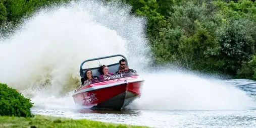 Jet boat kicking up water as it powers through a tight corner at Velocity Valley