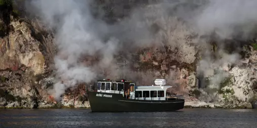The Ariki Moana boat cruising past steaming cliffs on Lake Rotomahana in Waimangu