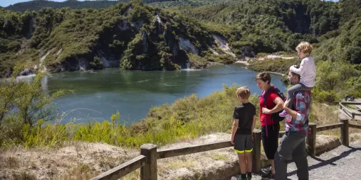 Family enjoying a scenic view over Frying Pan Lake in Waimangu Volcanic Valley, Rotorua