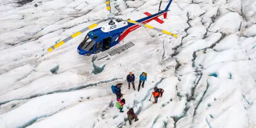 Helicopter landed on the Tasman Glacier with guests preparing for a private guided hike.