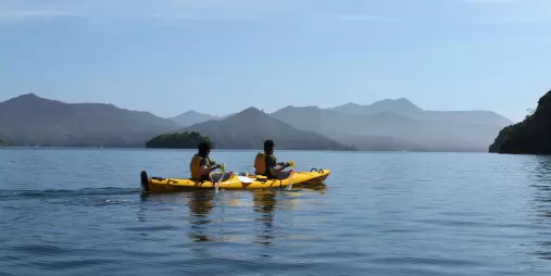 Two paddlers kayaking on smooth waters in Queen Charlotte Sound