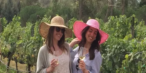 Two women in sunhats enjoying white wine in a Marlborough vineyard.
