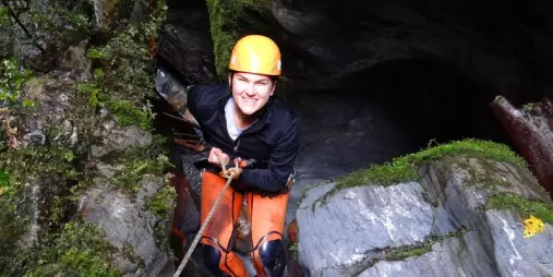 Adventurer abseiling into narrow rock walls at Blue Creek canyon