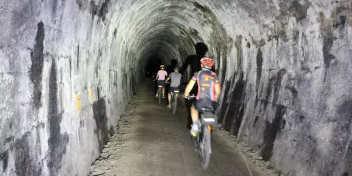 Cyclists ride through Spooners Tunnel on the Kiwi Journeys trail