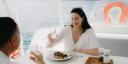 Couple enjoying lunch with white wine on a catamaran