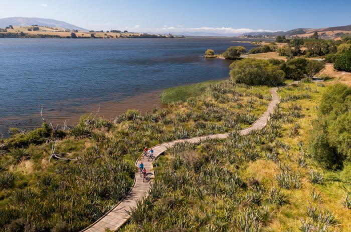 Cyclists riding along a boardwalk section of the Clutha Gold Trail extension between Lawrence and Milton in Central Otago, New Zealand