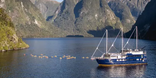 Wide view of the Fiordland Navigator with a group of kayakers in Doubtful Sound