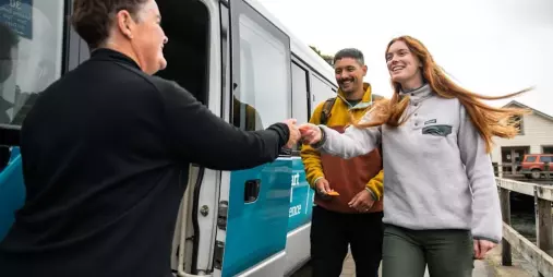 Guests boarding a bus with a warm welcome at the Stewart Island Ferry terminal.