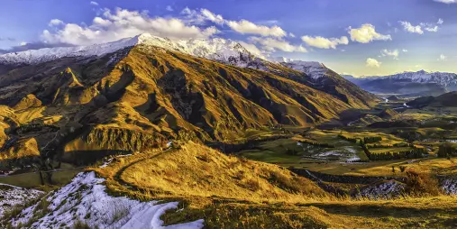 Snow-capped Remarkables mountain range with golden evening light near Queenstown