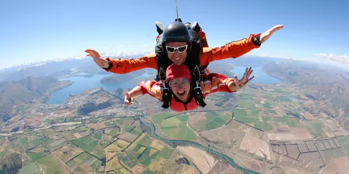 Skydivers freefalling above Wanaka’s patchwork farmland and lakes